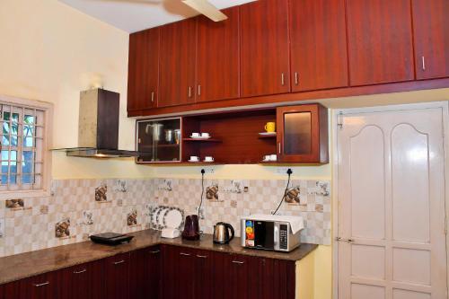 a kitchen with wooden cabinets and a microwave at Revive Inn Pondy - Rooms & Villa in Puducherry
