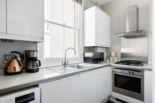cocina blanca con fregadero y microondas en Superb duplex in prime area of London, en Londres