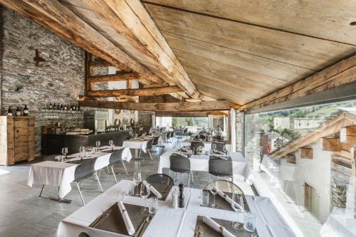un restaurant avec des tables blanches et des chaises blanches dans l'établissement Hotel Weiss Kreuz, à Splügen