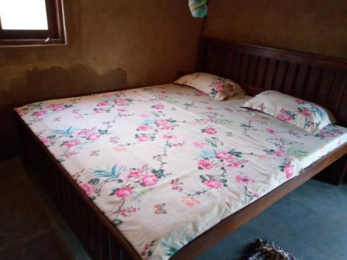 a bed with a floral bedspread and pillows on it at Ethili Lake view & Safari Camp in Wellawaya