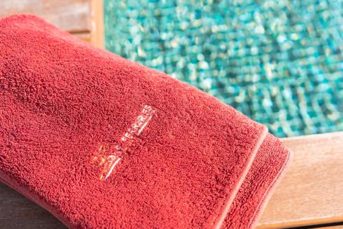 a red towel sitting next to a swimming pool at Hotel Loar Ferreries in Ferreries