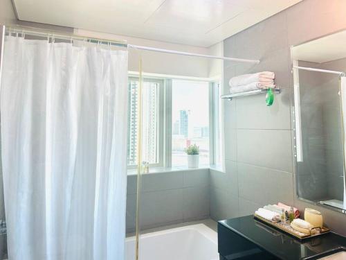 a bathroom with a shower curtain and a window at Sea View Cozy 2BHK Al Reem 6ppl - more than 10 days stay free transportation from Abu Dhabi Airport- in Abu Dhabi