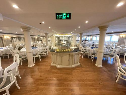 une salle de banquet avec des tables blanches et des chaises blanches dans l'établissement Orient MS Grand Rose, à Louxor