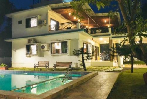 a house with a swimming pool in front of a house at Wildwood Retreat - Awas Beach in Avas