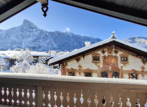 a house with a snowy roof with mountains in the background at Neu! Moderner bayrischer Flair vor Pilatushaus in Oberammergau