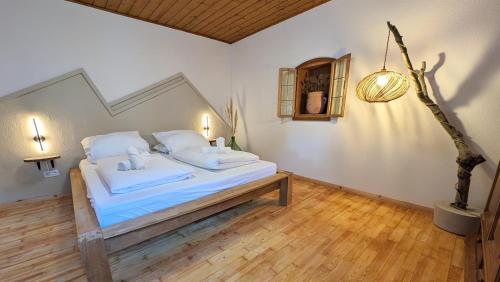 a bedroom with a bed with white sheets and a wooden floor at Neu! Moderner bayrischer Flair vor Pilatushaus in Oberammergau