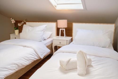 two white beds in a room with a skylight at Neu! Moderner bayrischer Flair vor Pilatushaus in Oberammergau