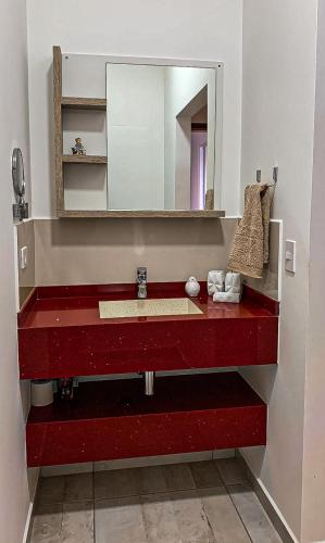 a bathroom with a red sink and a mirror at Refúgio Vila da Glória in São Francisco do Sul