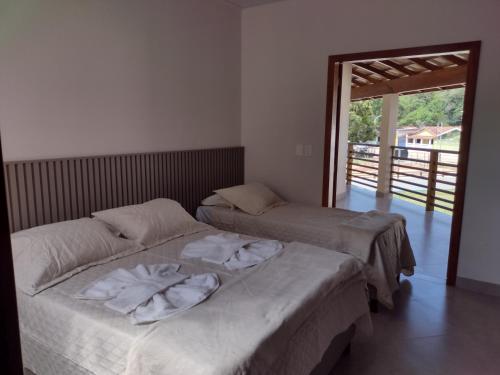 een slaapkamer met 2 bedden en een deur naar een balkon bij Pousada Pantanal in Prado