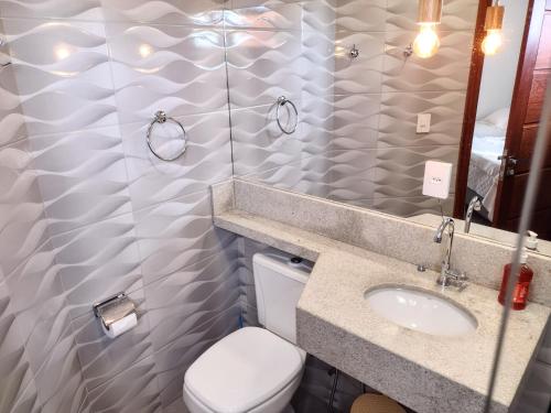een badkamer met een toilet, een wastafel en een spiegel bij Pousada Pantanal in Prado