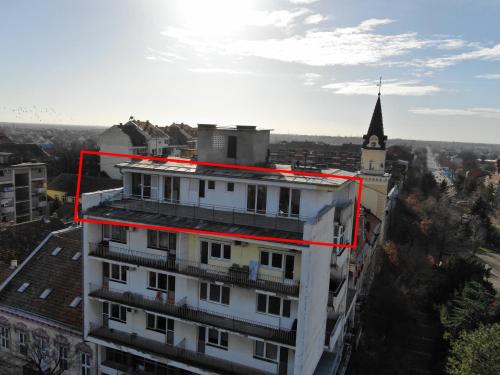 a white building with a red rectangle on top of it at Fleur de Lys in Kikinda