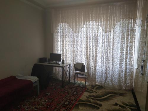 a bedroom with a desk and a window with a laptop at Дачный домик in Tashkent