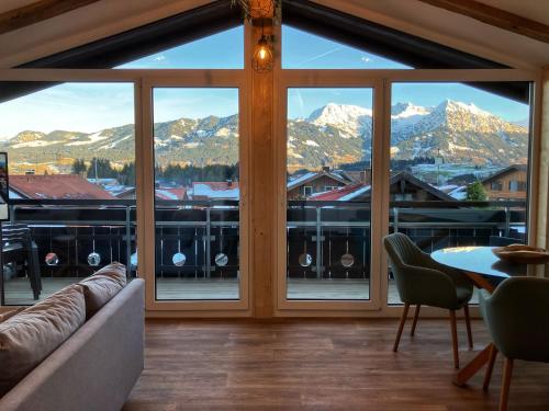 a living room with a large window with a view of mountains at Landhaus Speiser in Bolsterlang