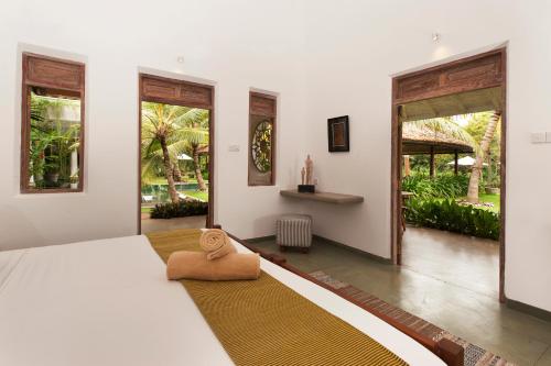 a bedroom with a large white bed and windows at Nirbana Retreat in Ahangama