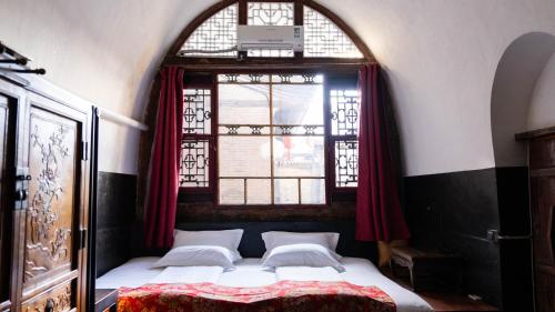 Bett in einem Zimmer mit Fenster in der Unterkunft Pingyao Yide Hotel in Pingyao