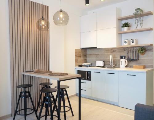 a kitchen with white cabinets and a table with stools at Milmari Apartments Pahulja N Lux in Kopaonik