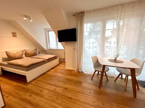 a bedroom with a bed and a table and a window at K8 FeWo - Am Kurpark - Therme in Bad Saarow