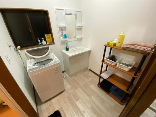baño pequeño con lavabo y lavadora en 一棟貸しの宿 OKAYADO, en Oshima