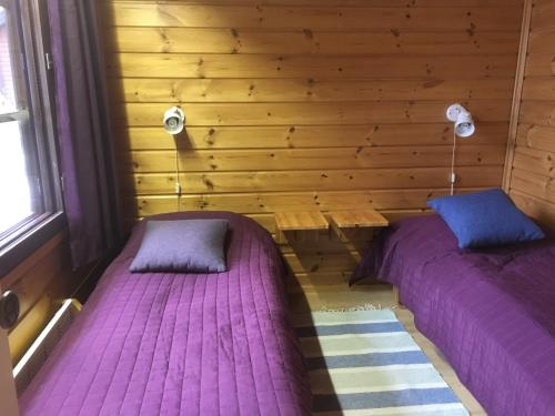 two beds in a room with wooden walls at Tahkon mökki in Tahkovuori