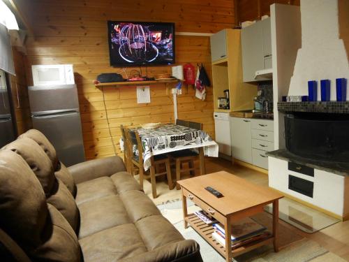 a living room with a couch and a table in a kitchen at Tahkon mökki in Tahkovuori