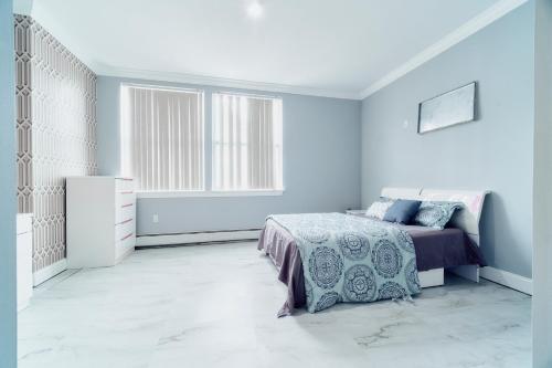 een witte slaapkamer met een bed en een raam bij Waterfront Gem Duplex 3 Bedroom 2Floor in Whitestone Bronx Free parking in College Point