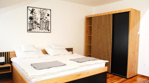een slaapkamer met een bed en een kast bij Liget Apartman in Pusztaszabolcs