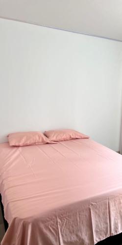 a bed with pink sheets and a white wall at senderos de Guayacán torre 2 apto 708 in Girardot