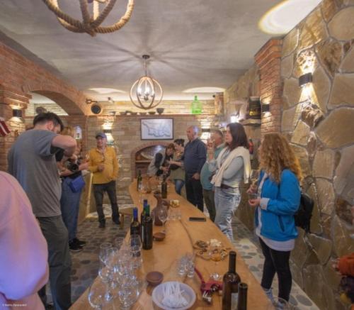a group of people standing around a bar with wine glasses at Guest House Okropilauri in Shuakhevi