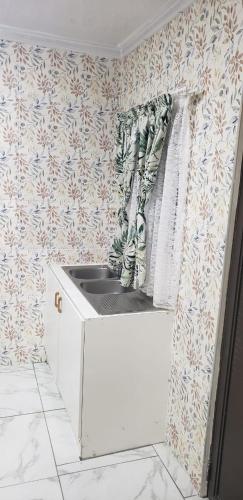 a kitchen with a sink in a room with wallpaper at 13 Maitland Road in King Williamʼs Town