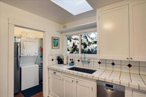 a kitchen with white cabinets and a sink and a window at Hammonds Beach Haven in Santa Barbara