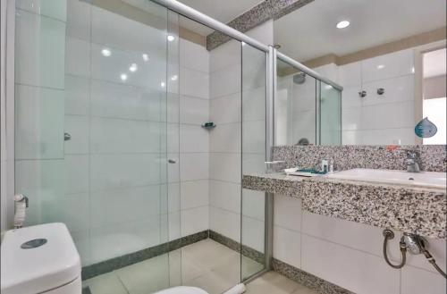 uma casa de banho com um chuveiro, um WC e um lavatório. em Flat com Varanda-Pampulha em Belo Horizonte