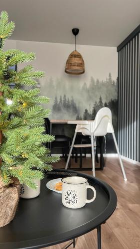 a table with a christmas tree and a coffee cup at Gojka Apartamenty in Piekielnik