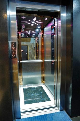 PerumpāvūrにあるUNIVERSAL RESIDENCYの鏡付きの部屋のガラス張りのエレベーター