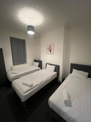two beds in a room with white sheets at 4 Bedroom House, Central City Location in Newcastle upon Tyne