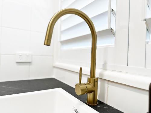 a kitchen sink with a gold faucet at Solhaus - Modern 1BR by Towradgi Beach in Towradgi