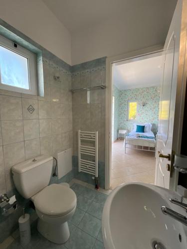 a bathroom with a toilet and a sink and a bedroom at Villa Kaminia Rose private pool & Jacuzzi in Ratzaklíon