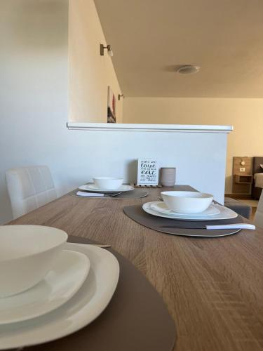 a table with white plates and bowls on it at Studio Apartman Nika in Višnjan