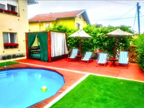 a pool with chairs and umbrellas next to a house at Villa Saturea in Boljevac