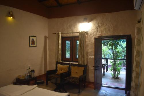 a bedroom with a bed and a chair and a window at Aranyak Resort in Tāla