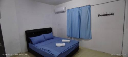 um quarto com uma cama azul com duas toalhas em MY HOMESTAY PANGSAPURI SUTERA 2 em Kampong Telok