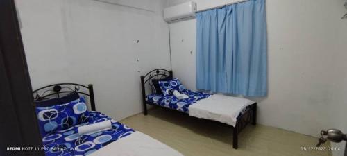 um quarto com 2 camas e uma janela com cortinas azuis em MY HOMESTAY PANGSAPURI SUTERA 2 em Kampong Telok