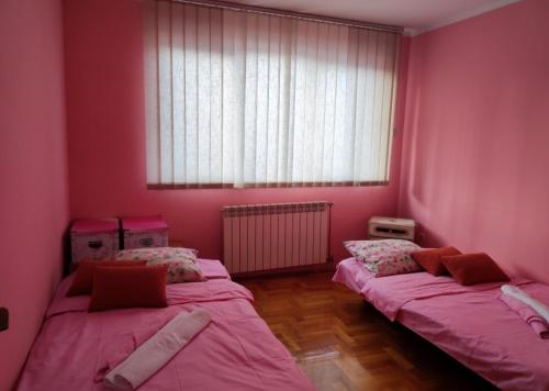 two beds in a room with pink walls and a window at Stan na dan Pale Apartman Danica in Pale