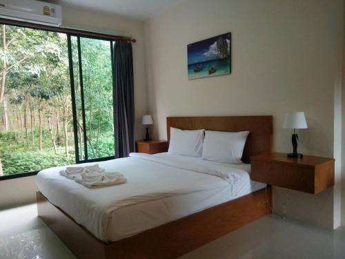 a bedroom with a large bed with a large window at Sj House Hotel Aonang in Ban Khlong Haeng