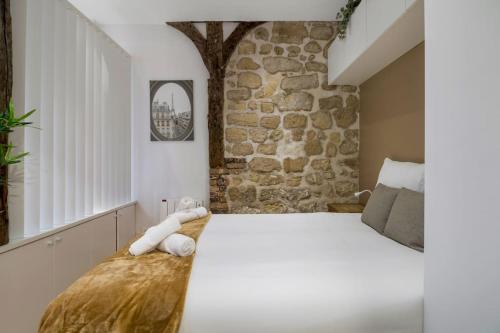 une chambre avec un grand lit avec un mur en pierre dans l'établissement Typical Parisian Studio in Le Marais#4 pers, à Paris