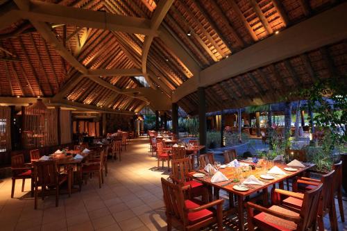 a restaurant with wooden tables and chairs and a ceiling at Shandrani Beachcomber Resort & Spa in Blue Bay