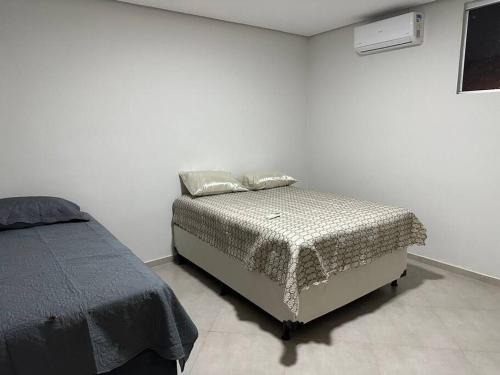 Dieses weiße Zimmer verfügt über ein Bett mit einer Bettdecke. in der Unterkunft Apartamento com vista para palco festival in Chapada dos Guimarães