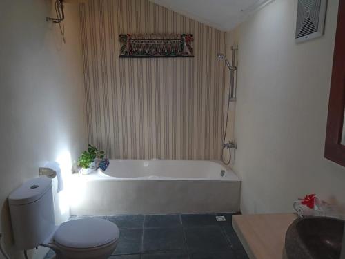 ein Badezimmer mit einer weißen Badewanne und einem WC in der Unterkunft Rosella Cottage - Homestay - Kitchen Yogyakarta in Yogyakarta