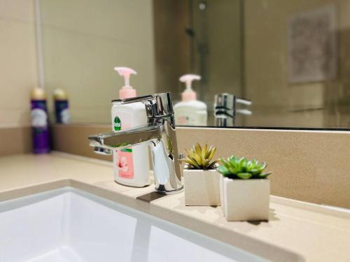 a bathroom sink with a faucet and two plants at Full Canal View Apartment at Yas Island- Brand New in Abu Dhabi