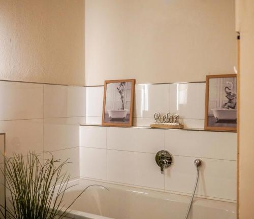un bagno con vasca e 2 immagini appese alla parete di Exklusives Stadthaus-Apartment am Staatstheather a Cottbus