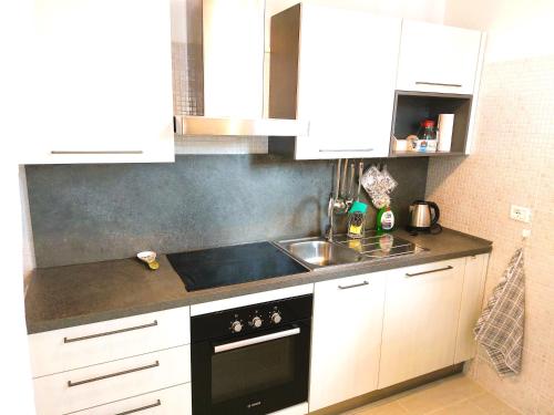 a kitchen with white cabinets and a black stove top oven at Appartamento Gioia Lugo a 5m da Maria Cecilia Hospital in Lugo